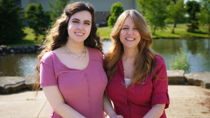 Female with dark brown hair and pink shirt on the left, female with light brown hair and burgundy shirt in the right. RVC pond is in the background.