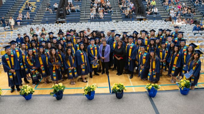 Graduates in caps and gowns pose for a group photo