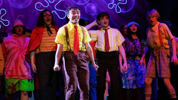 a group of diverse performers in brightly colored costumes