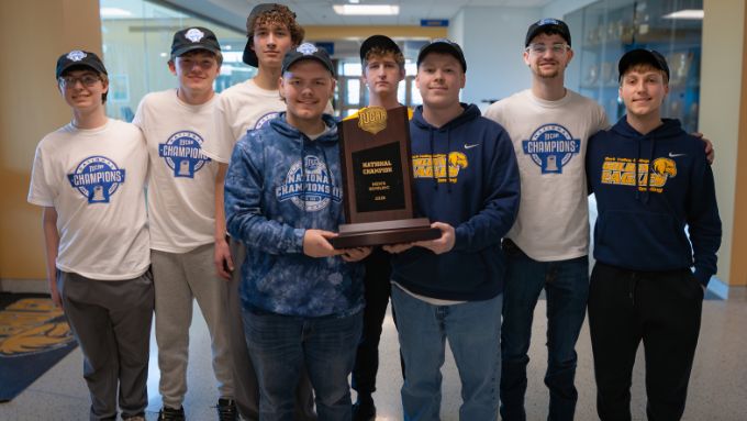 Eight Caucasian young men wearing championship gear, two are holding a bowling trophy