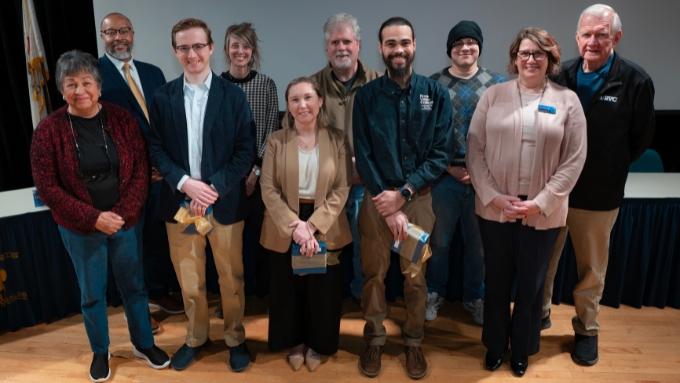 a diverse group of adults stand in front of board meeting tables