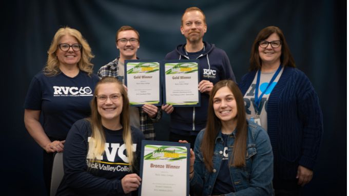 six white adults pose with three award certificates