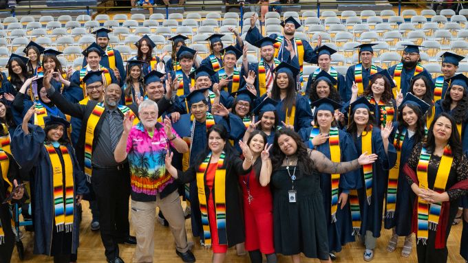 a diverse group of people in navy graduation caps and gowns