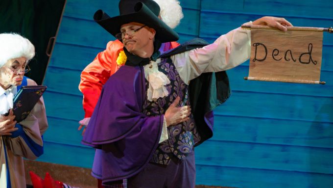 Performer on stage holdiing a sign that says Dead