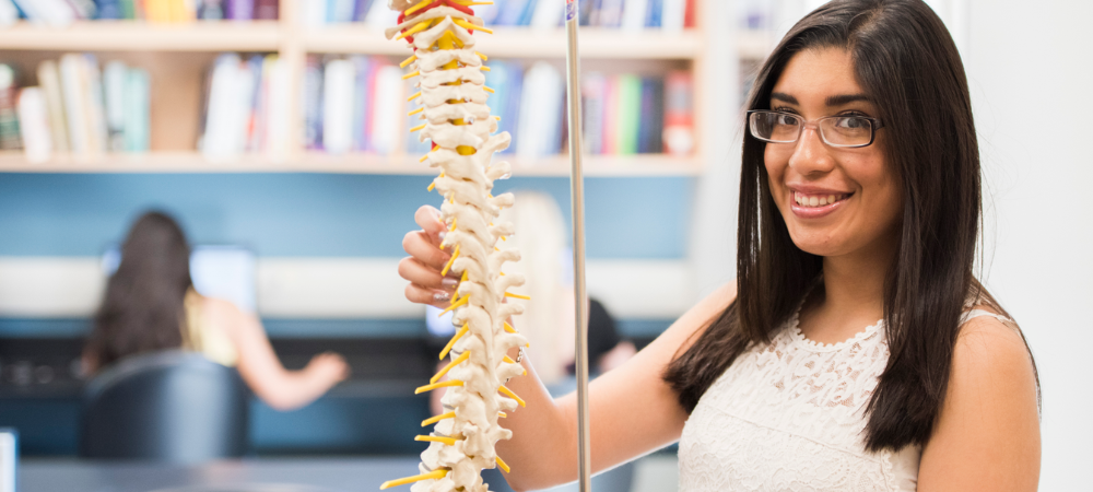 student pointing to spine of skeleton